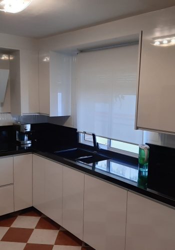 Cocina en blanco brillo, con encimera en granito negro y barra comunicada con el salón 1 (10)