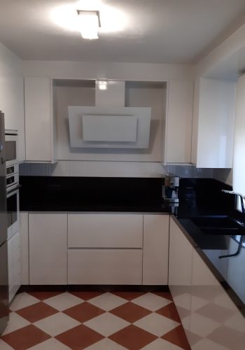 Cocina en blanco brillo, con encimera en granito negro y barra comunicada con el salón 1 (11)