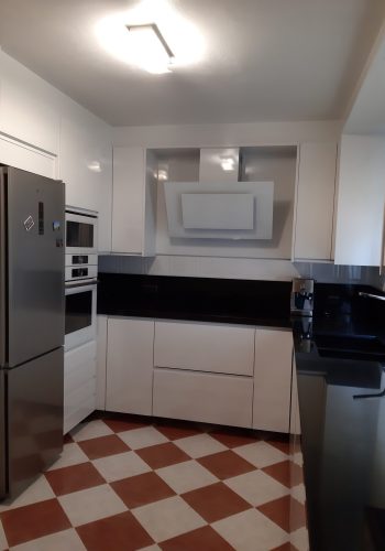 Cocina en blanco brillo, con encimera en granito negro y barra comunicada con el salón 1 (12)