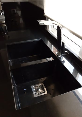 Cocina en blanco brillo, con encimera en granito negro y barra comunicada con el salón 1 (13)