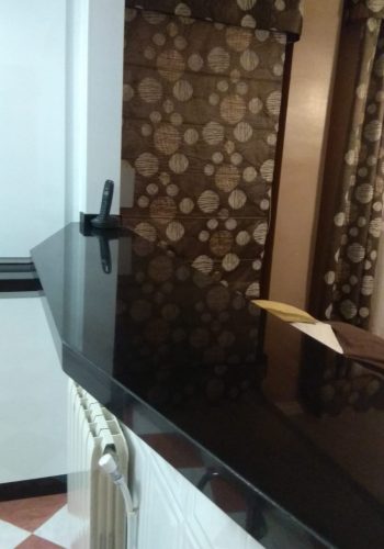 Cocina en blanco brillo, con encimera en granito negro y barra comunicada con el salón 1 (2)