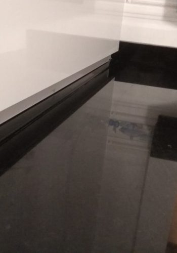 Cocina en blanco brillo, con encimera en granito negro y barra comunicada con el salón 1 (20)