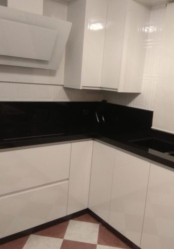 Cocina en blanco brillo, con encimera en granito negro y barra comunicada con el salón 1 (21)
