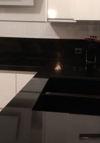 Cocina en blanco brillo, con encimera en granito negro y barra comunicada con el salón 1 (22)