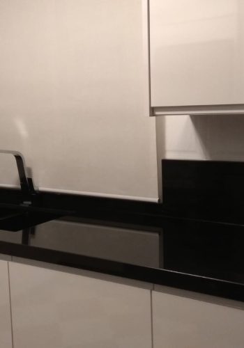 Cocina en blanco brillo, con encimera en granito negro y barra comunicada con el salón 1 (26)