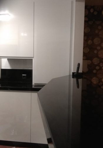 Cocina en blanco brillo, con encimera en granito negro y barra comunicada con el salón 1 (29)